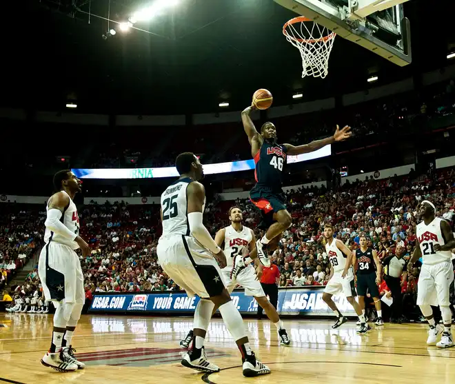 Jogador de basquetebol em pleno afundanço durante um jogo